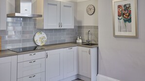 A modern kitchen with white cabinets, a stainless steel range hood, and a tiled backsplash.