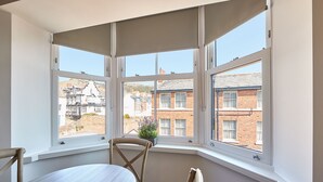 A corner room with a bay window, a round table, and a chair. - Host Stay Laguz The Merchants Quarters (Scarborough)