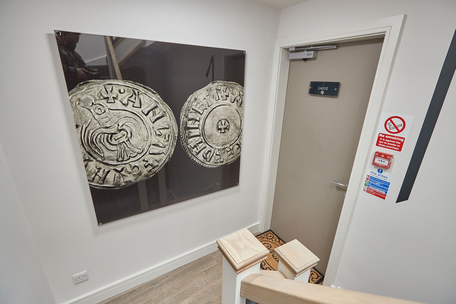 A hallway with a door labeled "LAGUZ" and a "No Smoking" sign. There are two large, circular wall decorations with intricate designs.