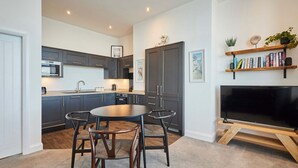 A modern kitchen with dark cabinets, a central island, and a dining area with chairs. - Host Stay Seaview Retreat (Whitby)