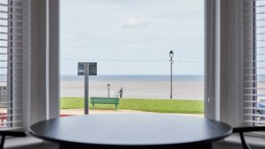 A view from a window overlooking a beach with a bench and a lamppost. - Host Stay Seaview Retreat (Whitby)