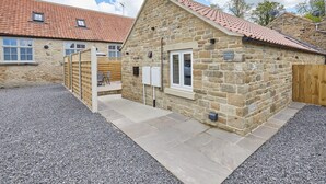 A stone building with a tiled roof, a wooden gate, and a gravel driveway. - Host Stay Sunny Dale Cottage (Pickering)
