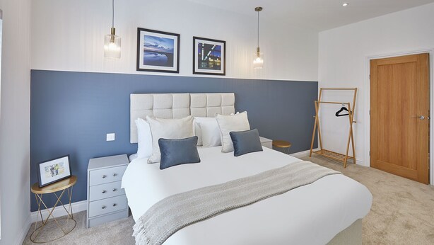 A bedroom with a large bed, a bedside table, a wardrobe, and a wooden door. - Host Stay Licence to Chill (Saltburn-by-the-Sea)