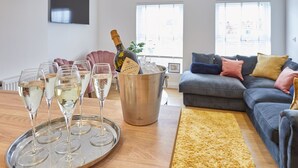 A living room with a sofa, a coffee table with glasses of champagne, and a bottle of champagne in a bucket. - Host Stay Licence to Chill (Saltburn-by-the-Sea)
