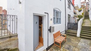 A narrow street with a white building, a wooden bench, and a staircase leading to another building. - Host Stay 11 Bakehouse Yard (Whitby)