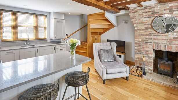 A modern kitchen with a central island, wooden flooring, a fireplace, and a staircase. - Host Stay 11 Bakehouse Yard (Whitby)