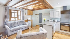 A modern kitchen with wooden beams, a grey sofa, and a small island. - Host Stay 11 Bakehouse Yard (Whitby)