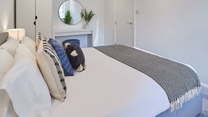 Ein modernes Schlafzimmer mit einem großen Bett, einem runden Spiegel, einem Kamin und einer Tür.