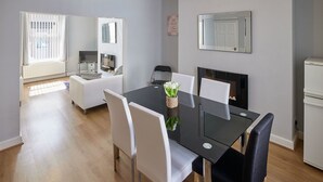 A modern kitchen with a stove, a dining table with chairs, and a refrigerator. - Host Stay 1 Oswy Street (Whitby)