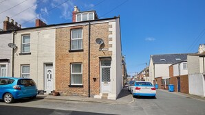 A street view with a two-story building, a parked car, and a clear blue sky. - Host Stay 1 Oswy Street (Whitby)