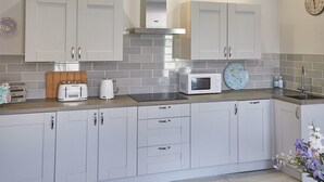 A modern kitchen with white cabinets, a stainless steel range hood, a microwave, and a toaster. - Host Stay The Runswick at Brunswick Holiday Apartments (Whitby)