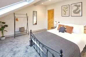 A bedroom with a bed, a hanging chair, a potted plant, and artwork on the walls.