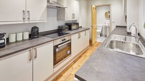 Una cocina moderna con electrodomésticos de acero inoxidable, horno integrado y un lavamanos grande.