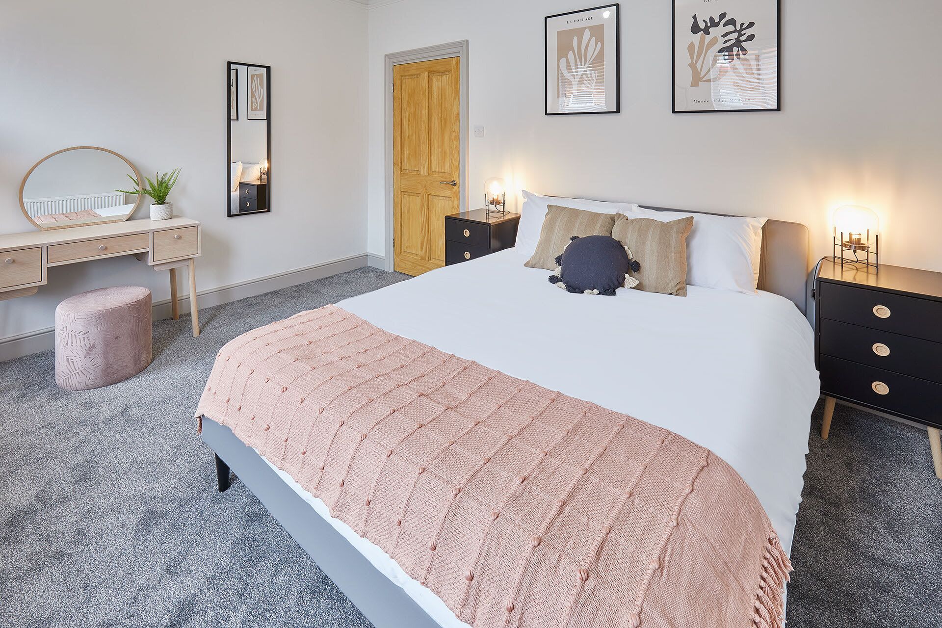 Une chambre à coucher comprenant un lit, des tables de chevet, une commode, un miroir et des œuvres d’art accrochées aux murs.