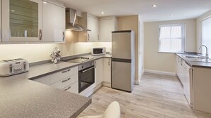 A modern kitchen with a granite countertop, stainless steel appliances, and a central island. - Host Stay The Cottage Bagdale Hall (Whitby)