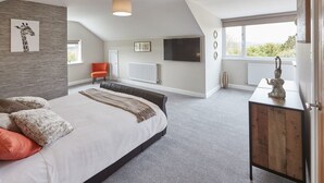 A bedroom with a bed, a chair, a dresser, a TV, and a window with a view. - Host Stay Badgers Cottage (Saltburn-by-the-Sea)