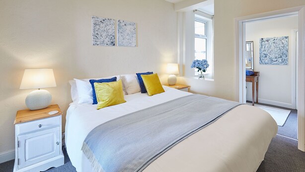 A neatly arranged bedroom with a bed, bedside tables, and a window with a view.