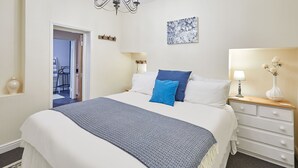A neatly arranged bedroom with a bed, bedside table, and a chandelier. - Host Stay Ocean Breeze (Scarborough)
