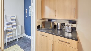 A compact kitchen with wooden cabinets, a microwave, a kettle, and a toaster. - Host Stay Ocean Breeze (Scarborough)