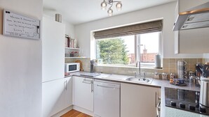 Une cuisine moderne avec des armoires blanches, un four à micro-ondes encastré, un évier et une fenêtre donnant sur l’extérieur.
