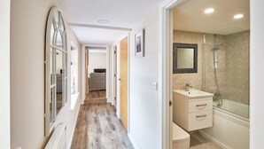 Corridoio che conduce a un bagno con doccia, lavandino e WC.