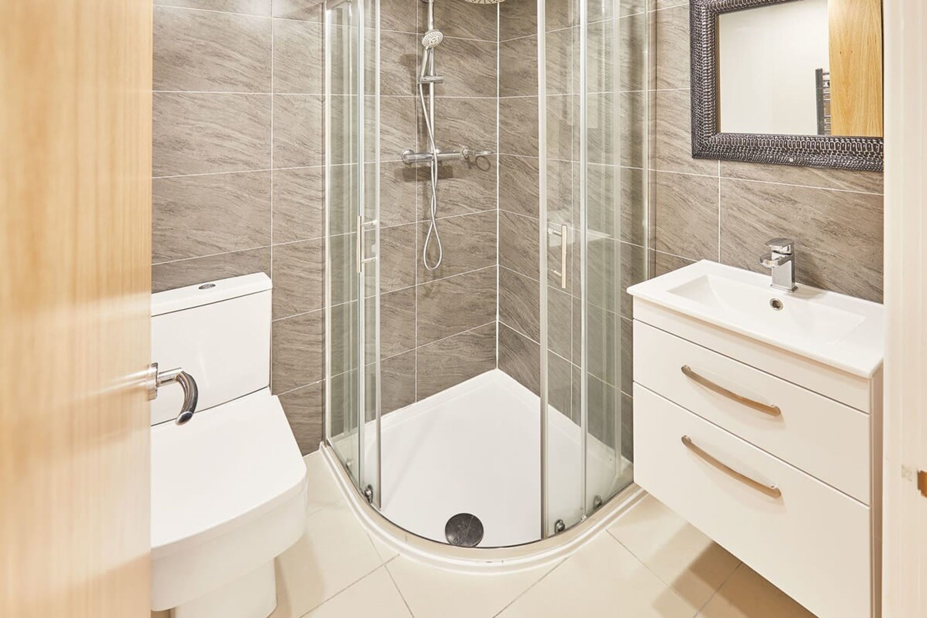Et moderne badeværelse med bruseniche, toilet og et underskab med skuffer.
