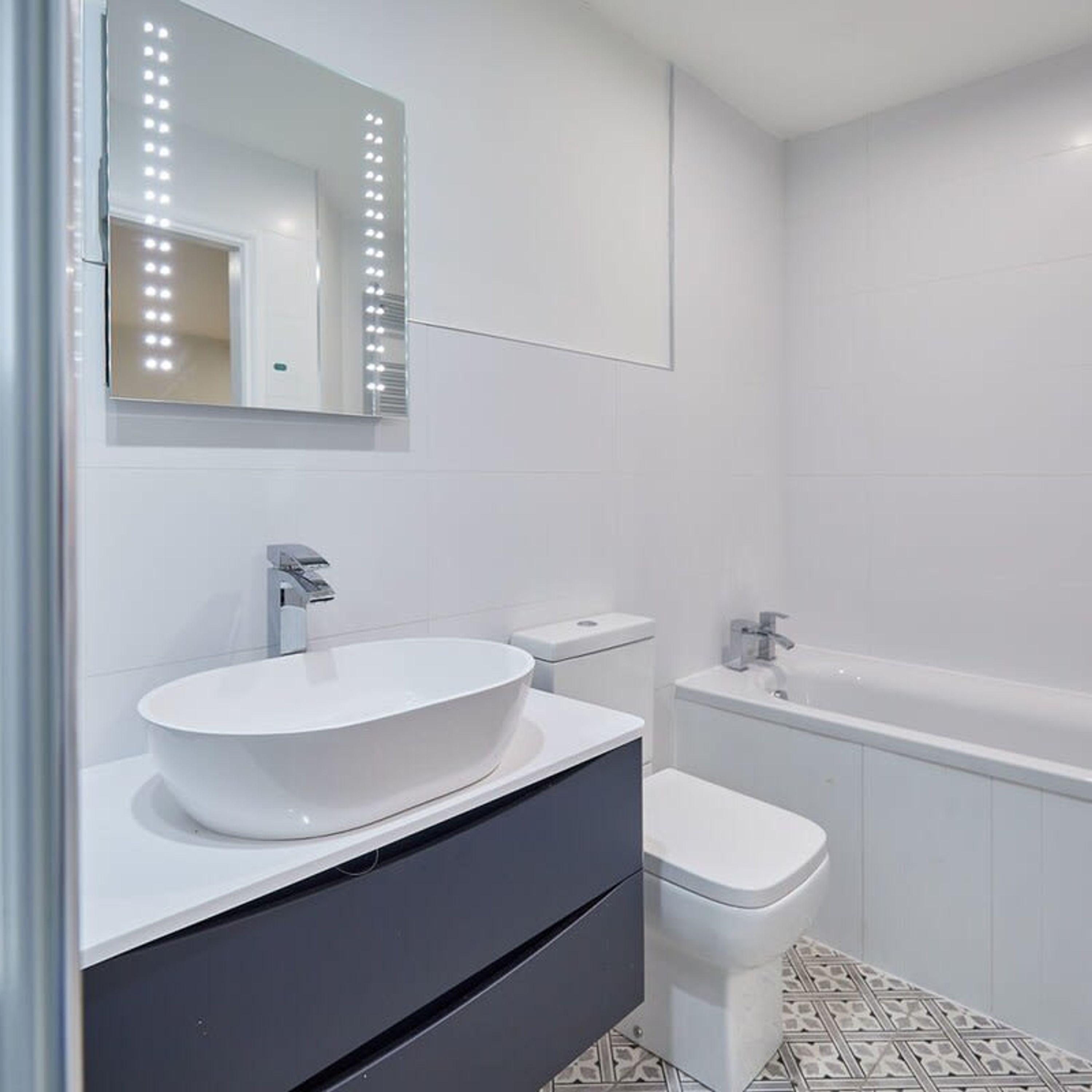 A modern bathroom with a white sink, vanity, and toilet.