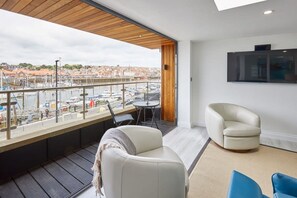 A balcony with a view of a marina and cityscape, furnished with a sofa, chairs, and a table. - Host Stay The Townhouse (Whitby)