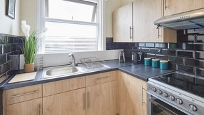 A modern kitchen with wooden cabinets, a stainless steel stove, and a black countertop. - Host Stay Ocean Wave (Scarborough)