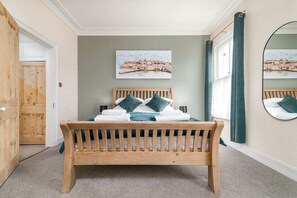 A bedroom with a wooden bed, a painting on the wall, and a mirror. - Host Stay Railman s Rest (Whitby)