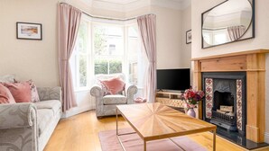 Una sala de estar con chimenea, un sofá, una mesa de centro y un televisor.