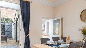 Un comedor con una mesa de madera dispuesta para cuatro, sillas grises y un espejo grande en la pared.