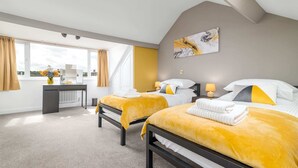 Una habitación de hotel moderna con dos camas, un escritorio y un amplio ventanal.