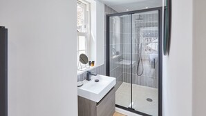 A modern bathroom with a glass shower enclosure, a white sink, and a mirror. - Host Stay Modern Industrial Golden Lion Apartments (Whitby)