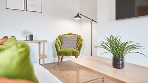 A modern living room with a green armchair, a wooden table, a floor lamp, and a potted plant. - Host Stay Whitby Heights (Whitby)