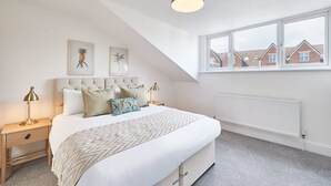 A bedroom with a large bed, a window with a view of houses, and a ceiling light. - Host Stay Whitby Heights (Whitby)