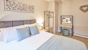 A neatly arranged bedroom with a bed, bedside table, mirror, and a radiator. - Host Stay The Avenue Victoria Apartment (Scarborough)