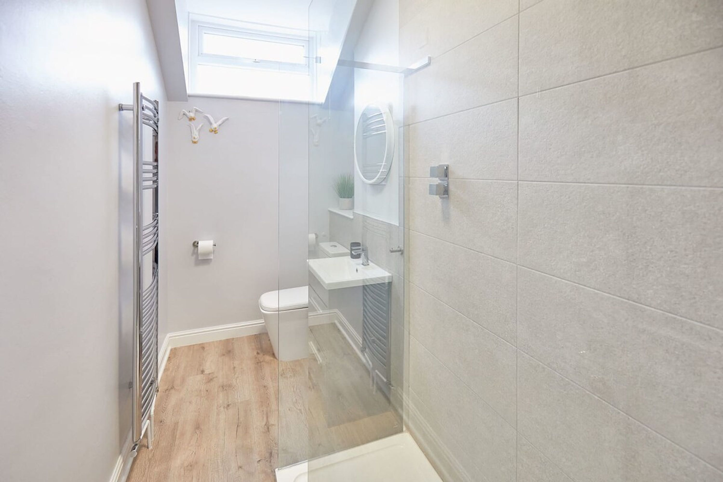 A modern bathroom with a glass shower enclosure, a white toilet, and a small sink.