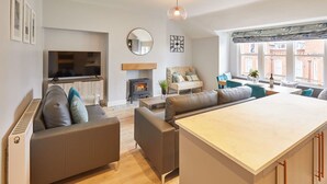 A modern living room with a fireplace, sofa, and a dining area. - Host Stay The Avenue Victoria Apartment (Scarborough)