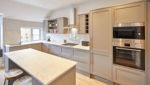 A modern kitchen with a central island, built-in appliances, and a window overlooking the city. - Host Stay The Avenue Victoria Apartment (Scarborough)