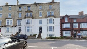 A row of terraced houses with a central entrance and a staircase leading to the front door. - Host Stay Sandy Cove (Saltburn-by-the-Sea)