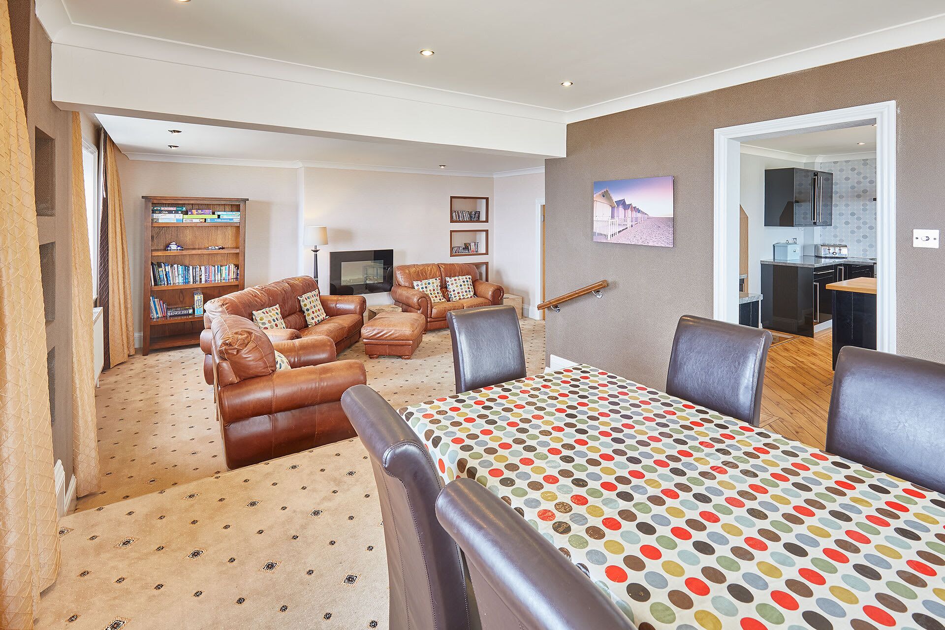 A living room with a sofa set, a TV, a bookshelf, and a dining area with a table.