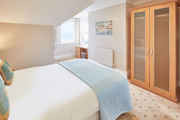 A bedroom with a bed, a wardrobe, a radiator, and a window with a view. - Host Stay Sea View 44 (Whitby)