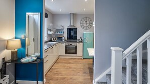 Une cuisine compacte dotée d’appareils électroménagers modernes, d’une horloge et d’un escalier menant à un autre niveau.