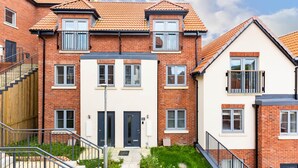 A multi-story residential building with a brick facade, white walls, and a tiled roof.