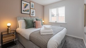 A neatly arranged bedroom with a bed, bedside tables, a window, and wall art.