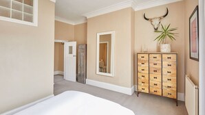 Ein Schlafzimmer mit Bett, Schminktisch, Spiegel und Wandpflanze.