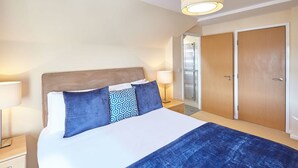 A hotel room with a bed, two bedside tables, a nightstand, a wardrobe, and a door. - Host Stay Abbey Horizon (Whitby)