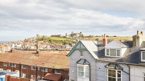 A coastal town with a prominent castle on a hill in the background. - Host Stay Abbey Horizon (Whitby)