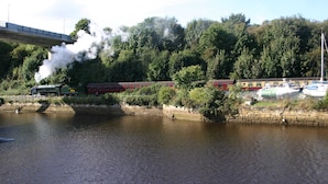 Une rivière avec un pont, un train et des bateaux.